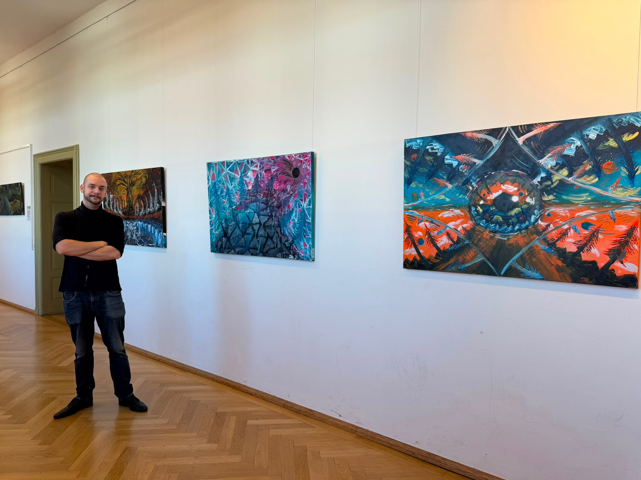 Portrait des Künstlers Julian Wesner vor einigen seiner Werke.